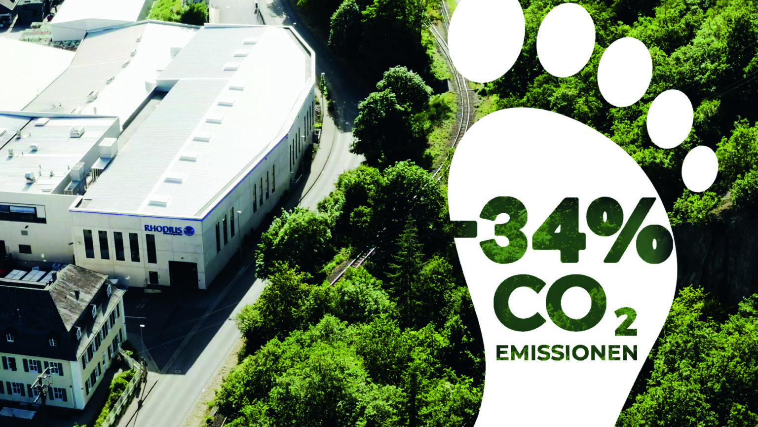 Wir legen sehr großen Wert auf Nachhaltigkeit. Ansicht auf das Firmengeländer von RHODIUS von oben. Am rechten Bildrand ist die Grafik von einem weißen Fußabdruck mit der Beschriftung –34% CO2 Emissionen eingefügt.